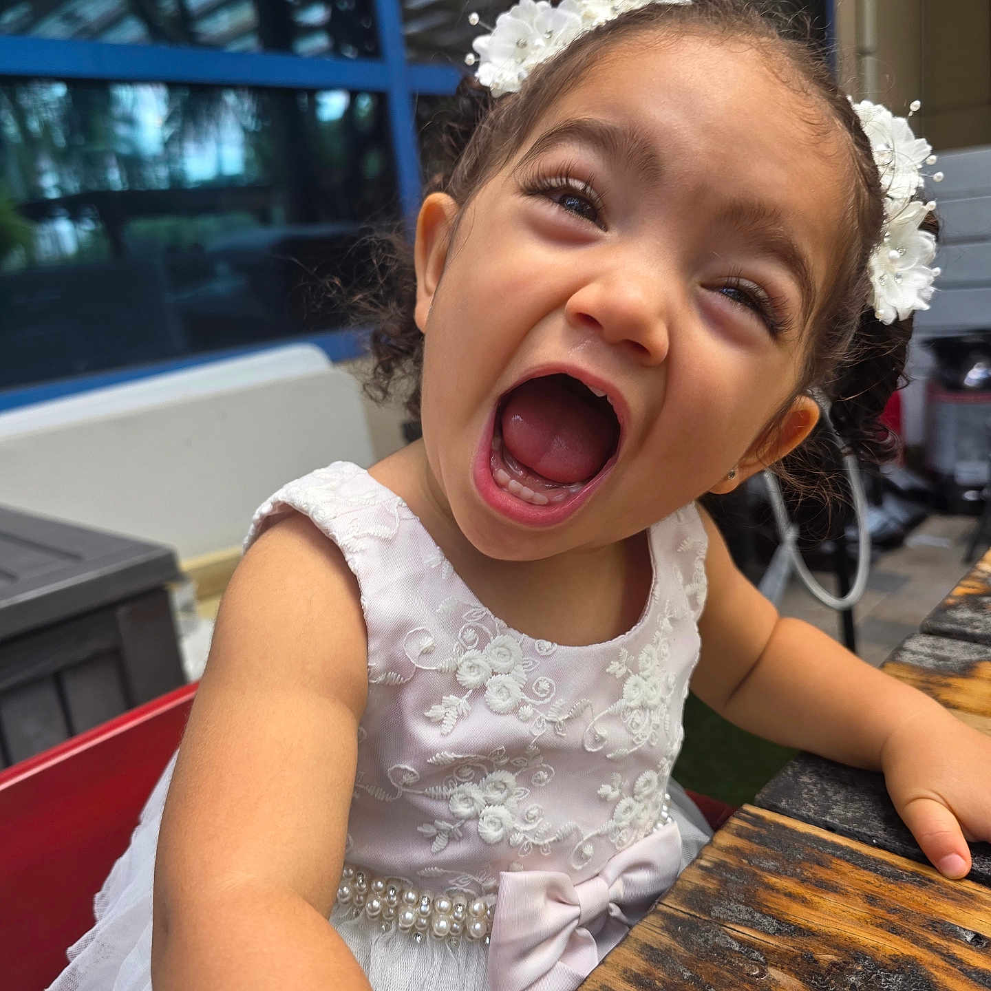 Isamary Sepulveda is registered to the contest to win money with this photo: child, closeup, fashion, floral_dress, girl, hair_accessories, happy, headband, indoor, laughing, open_mouth, playful, portrait, restaurant, seated, smiling, table, toddler, window, wooden_table