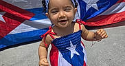 Isamary Sepulveda is registered to the contest to win money with this photo: baby, child, clothing, dress, flag, happy, headband, market, merchandise, outdoor, patriotic, portrait, puerto_rican_flag, red_white_blue, sandals, smiling, sunlight, toddler, vendor_stall, walking