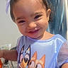 Isamary Sepulveda is registered to the contest to win money with this photo: bed, bedroom, blue_shirt, brown_hair, cartoon, child, closeup, clothing, curly_hair, curtain, dog_graphic, face, girl, happy, head, indoors, portrait, sitting, smiling, toddler