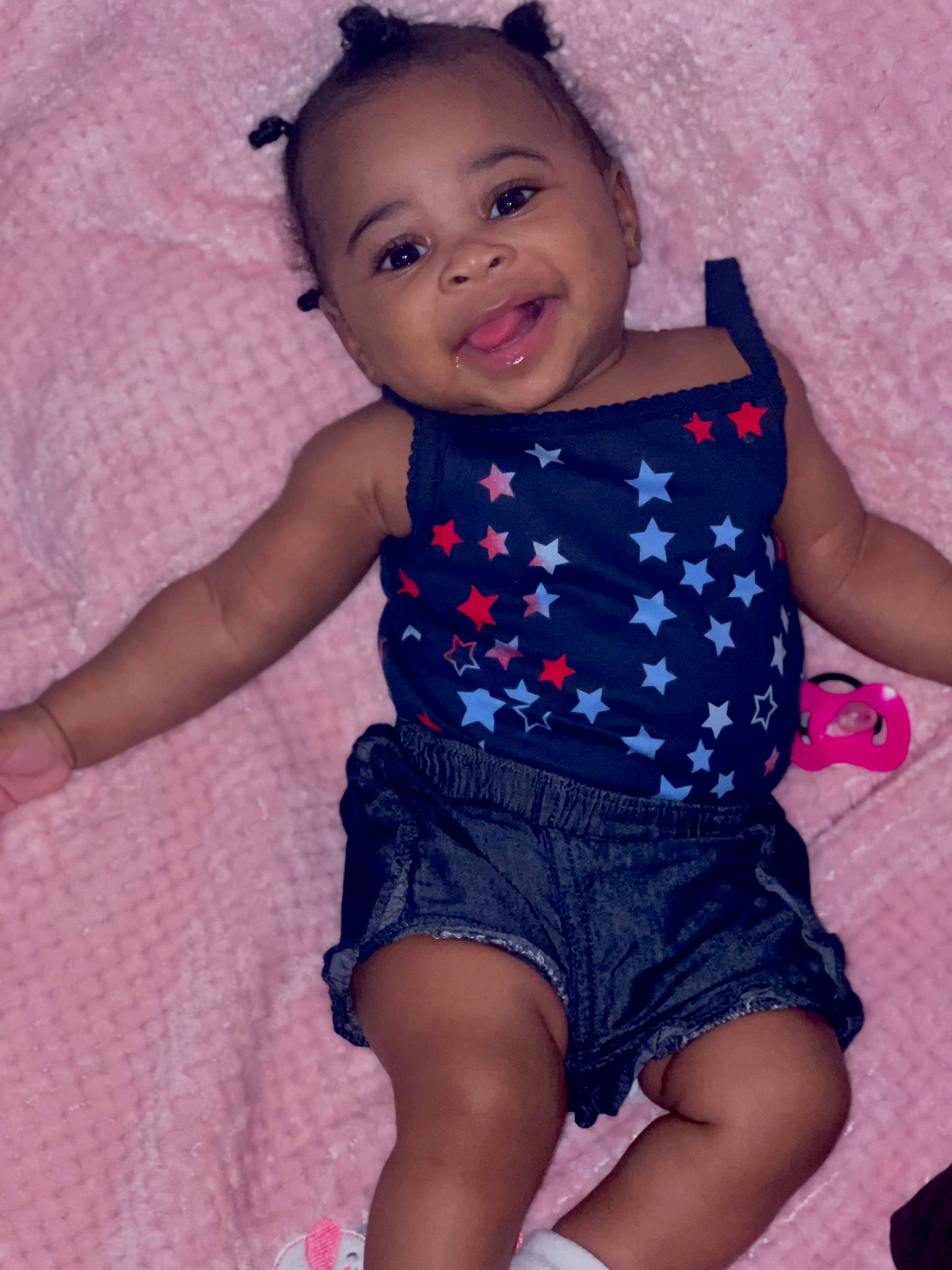 Samara is registered to the contest to win money with this photo: arm, baby_toddler_clothing, cheek, facial_expression, finger, hand, happy, iris, joint, mouth, neck, organ, person, pink, purple, shoulder, skin, sleeve, smile, textile