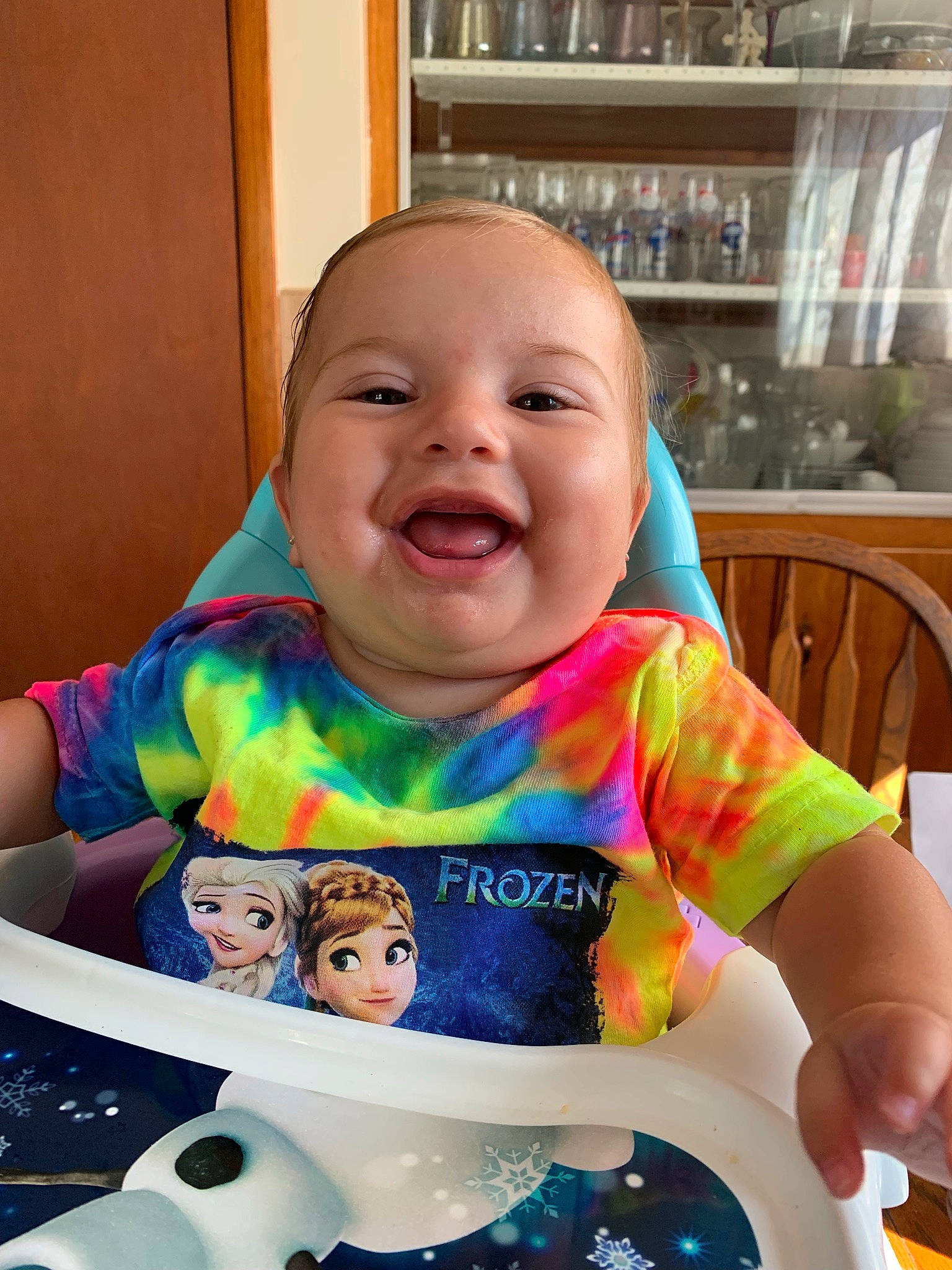 Annalee is registered to the contest to win money with this photo: baby, baby_toddler_clothing, bib, chair, cheek, chin, drinkware, facial_expression, finger, hairstyle, happy, organ, person, product, skin, sleeve, smile, standing, t_shirt, tableware