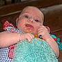 Oakley is registered to the contest to win money with this photo: baby, infant, blue_eyes, blanket, toy, hand, face, skin, clothing, pattern, red, blue, plush, comfort, indoor, person, cute, expression, child, toddler