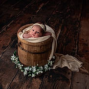 Oakley joined the competition — help win amazing prizes! baby, infant, wooden_bucket, blanket, flower_headband, flowers, wooden_floor, portrait, cute, newborn, soft_lighting, cozy, decor, child, wrapped, resting, baby_face, studio_photo, warm_tones, peaceful