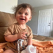 Drakeson is registered to the contest to win money with this photo: toddler, child, smile, happy, baby_bottle, pacifier, toy_story, woody, clothing, diaper, blanket, indoor, couch, hair, face, person, cute, living_room, furniture, infant