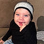 toddler, child, smiling, blue_eyes, beanie, black_sweater, denim_jeans, couch, indoor, cute, happy, portrait, sitting, finger_in_mouth, playful, baby, person, face, apparel, casual
