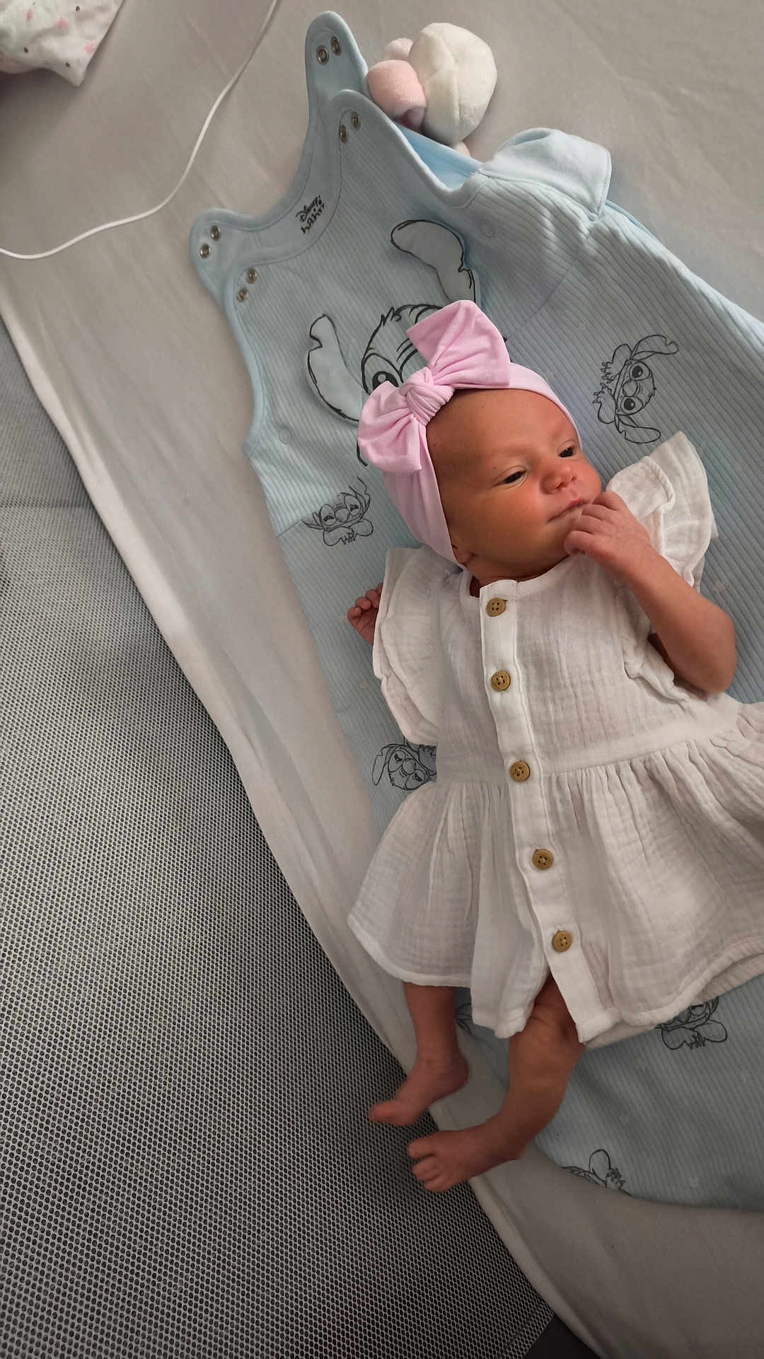 Nëylia participe au concours pour gagner de l'argent avec cette photo : newborn, baby, infant, white_dress, pink_bow, headband, blanket, disney, blue_blanket, lying_down, bed, soft_toys, cute, indoors, small_feet, hand_near_mouth, sleeping_area, child, portrait, resting