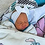 newborn, baby, sleeping, blanket, headband, bow, couch, pillow, cozy, indoors, child, face, resting, soft, cute, comfort, infant, textile, pattern, portrait