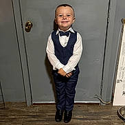 Xavier joined the competition — help win amazing prizes! child, boy, smile, suit, bow_tie, formal_wear, standing, door, indoor, floor, wood_floor, happy, portrait, person, clothing, shoes, young, cute, fashion, pose