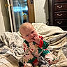 Peyton joined the competition — help win amazing prizes! baby, bedroom, blanket, child, cozy, cute, door, dresser, expression, face, floor, furniture, hand, home_interior, indoor, infant, light_switch, pajamas, sitting, wood_paneling