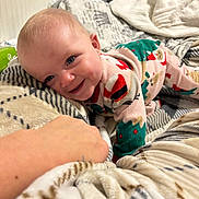 Peyton is registered to the contest to win money with this photo: baby, child, smiling, pajamas, blanket, hand, blue_eyes, indoor, cute, cozy, infant, patterned_blanket, happy, person, portrait, lying_down, soft_texture, holiday_theme, warm, comfort