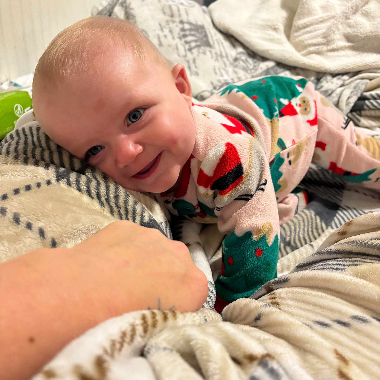 Peyton is registered to the contest to win money with this photo: baby, child, smiling, pajamas, blanket, hand, blue_eyes, indoor, cute, cozy, infant, patterned_blanket, happy, person, portrait, lying_down, soft_texture, holiday_theme, warm, comfort