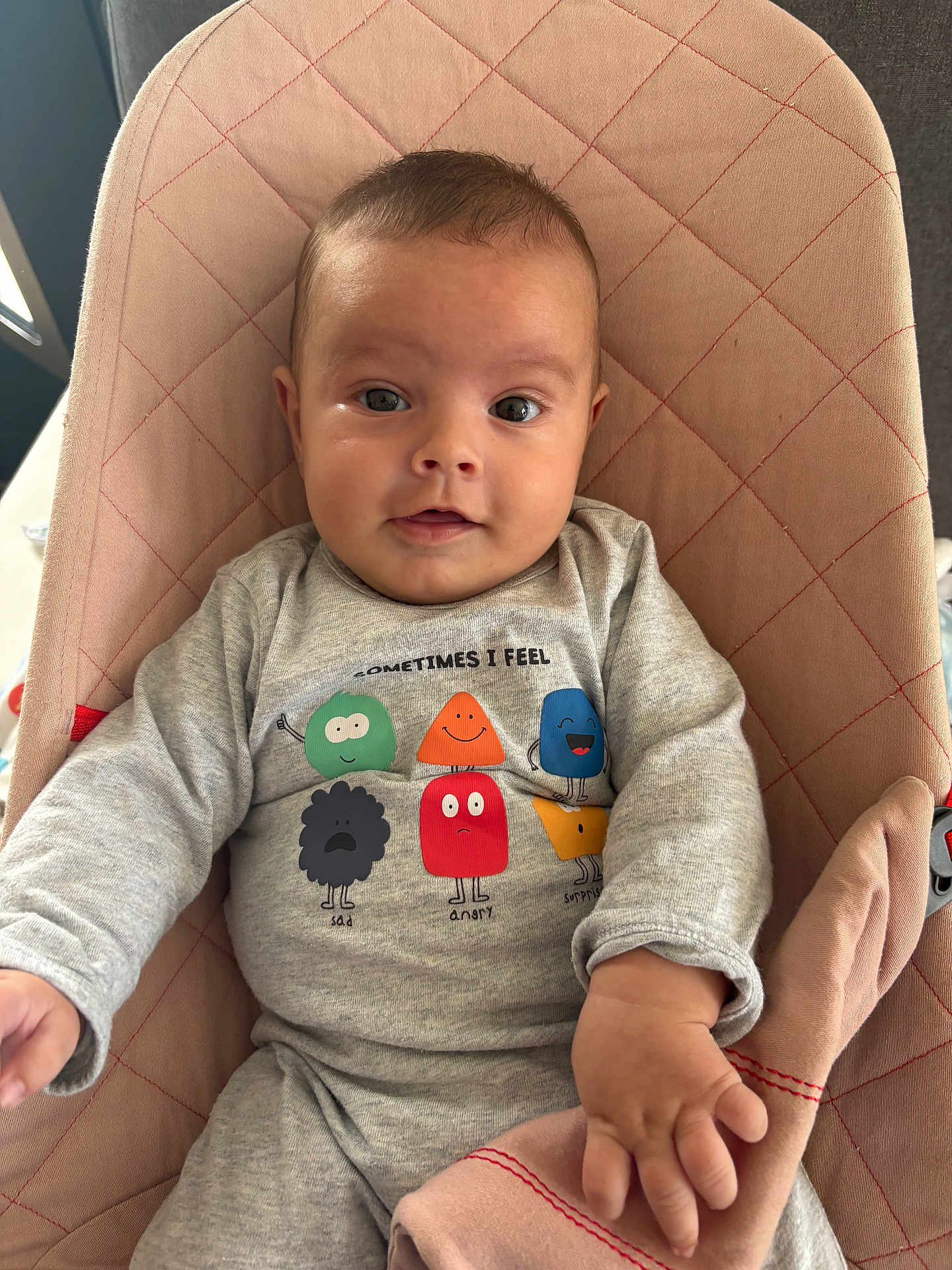 Tiago participe au concours pour gagner de l'argent avec cette photo : baby, infant, child, onesie, cartoon, emotions, quilted_chair, pink, grey_clothing, cute, portrait, indoor, hand, face, expression, seated, soft_fabric, clothing, smiling, young