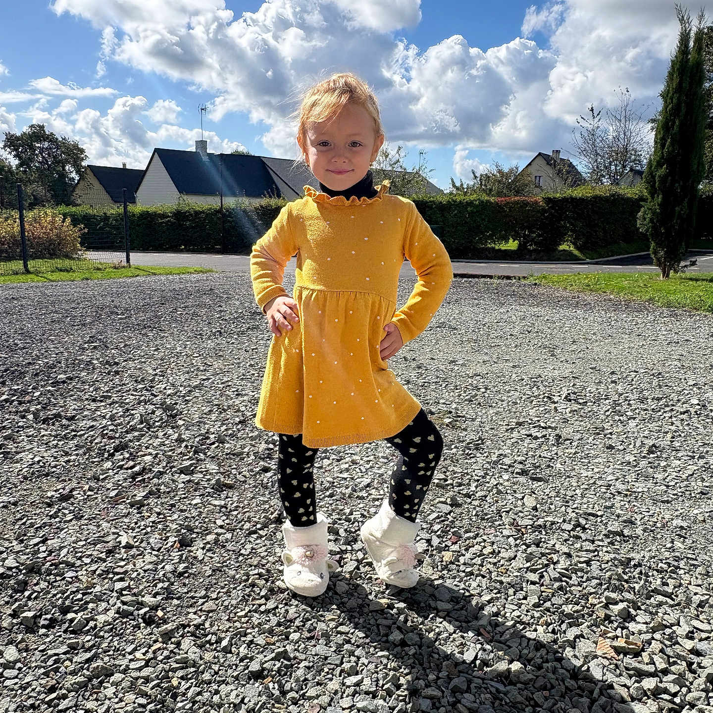 Angela a rejoint le concours — aidez-le/la à gagner de superbes lots ! black_tights, blue_sky, child, clouds, confident, daytime, girl, gravel, hands_on_hips, hedge, houses, outdoor, polka_dots, residential_area, shadow, smiling, sunny, trees, white_slippers, yellow_dress