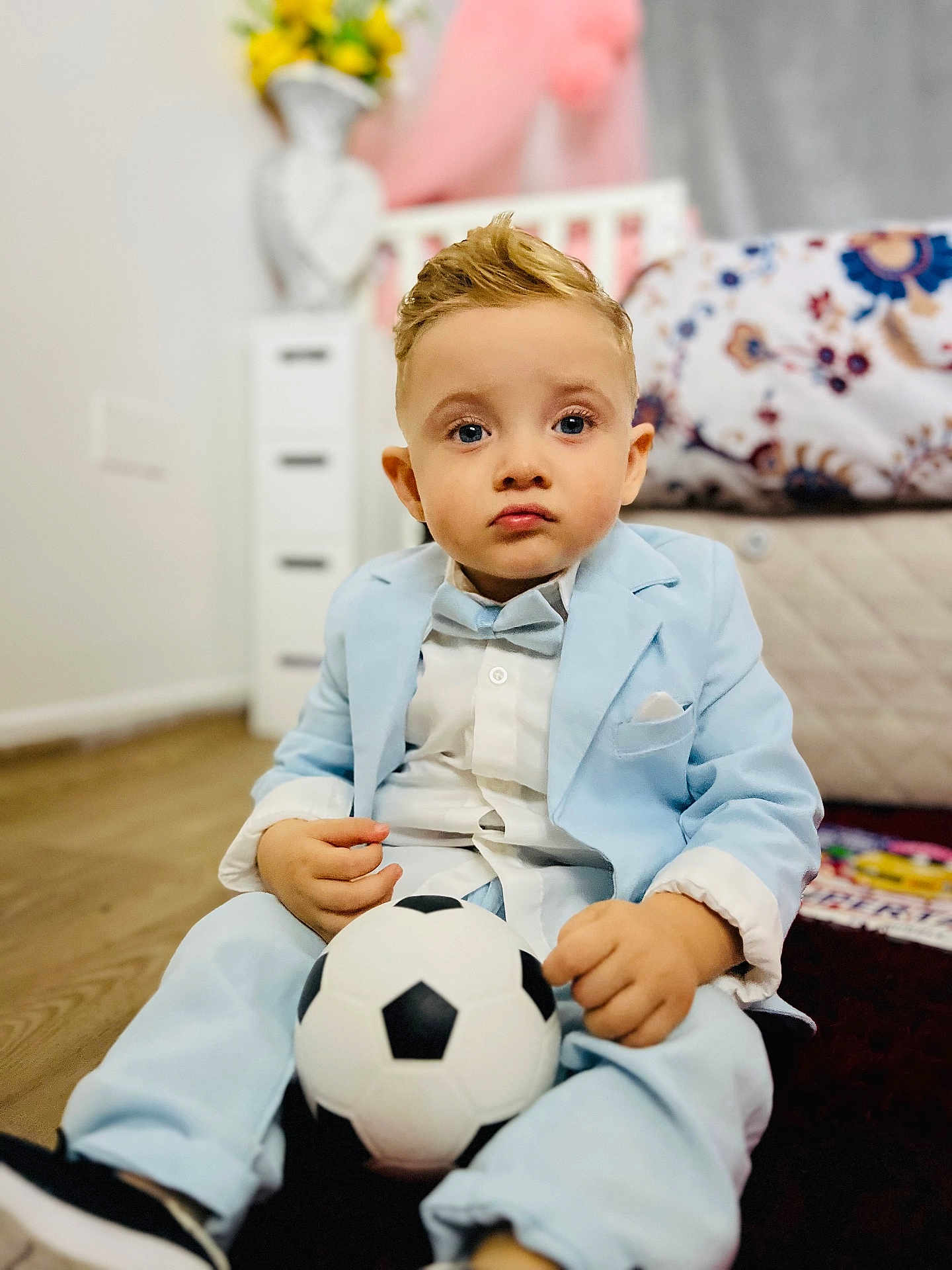 Iacov Isac Vasile joined the competition — help win amazing prizes! child, boy, suit, bow_tie, soccer_ball, indoor, carpet, bed, blanket, dresser, vase, flowers, wooden_floor, portrait, cute, serious_expression, home, furniture, clothing, person