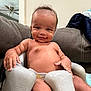 baby, child, smiling, diaper, seat, indoor, couch, furniture, person, skin, hand, arm, face, head, hair, dimples, comfort, relaxing, expression, living_room