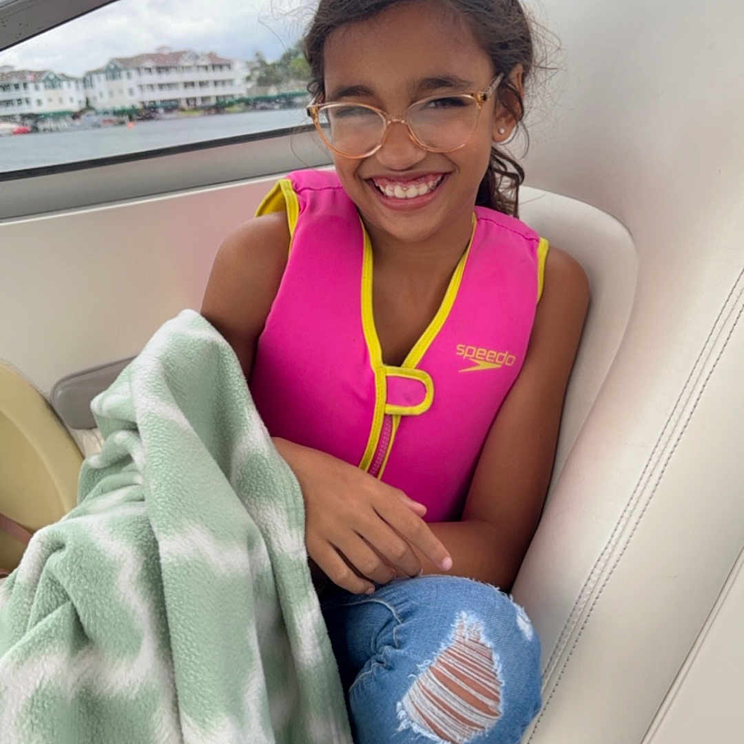 Melody is registered to the contest to win money with this photo: accessories, blanket, child, clothing, face, female, girl, glasses, happy, head, homedecor, lifejacket, pants, person, photography, portrait, shorts, smile, swimwear, vest