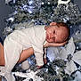baby, celebration, christmas_tree, closeup, cute, decorations, festive, hand, holiday, infant, lights, newborn, ornaments, person, portrait, sleepy, soft_lighting, sparkle, white_clothing, winter