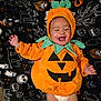 baby, pumpkin_costume, halloween, blanket, smiling, infant, cute, holiday, festive, costume, child, orange, green, fabric, pattern, lying_down, happy, face, diaper, celebration