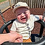 Luca is registered to the contest to win money with this photo: baby, child, swing, playground, cap, smile, happy, hand_holding, outdoor, sunlight, fence, wood, mulch, clothing, seat, person, daytime, recreation, fun, park