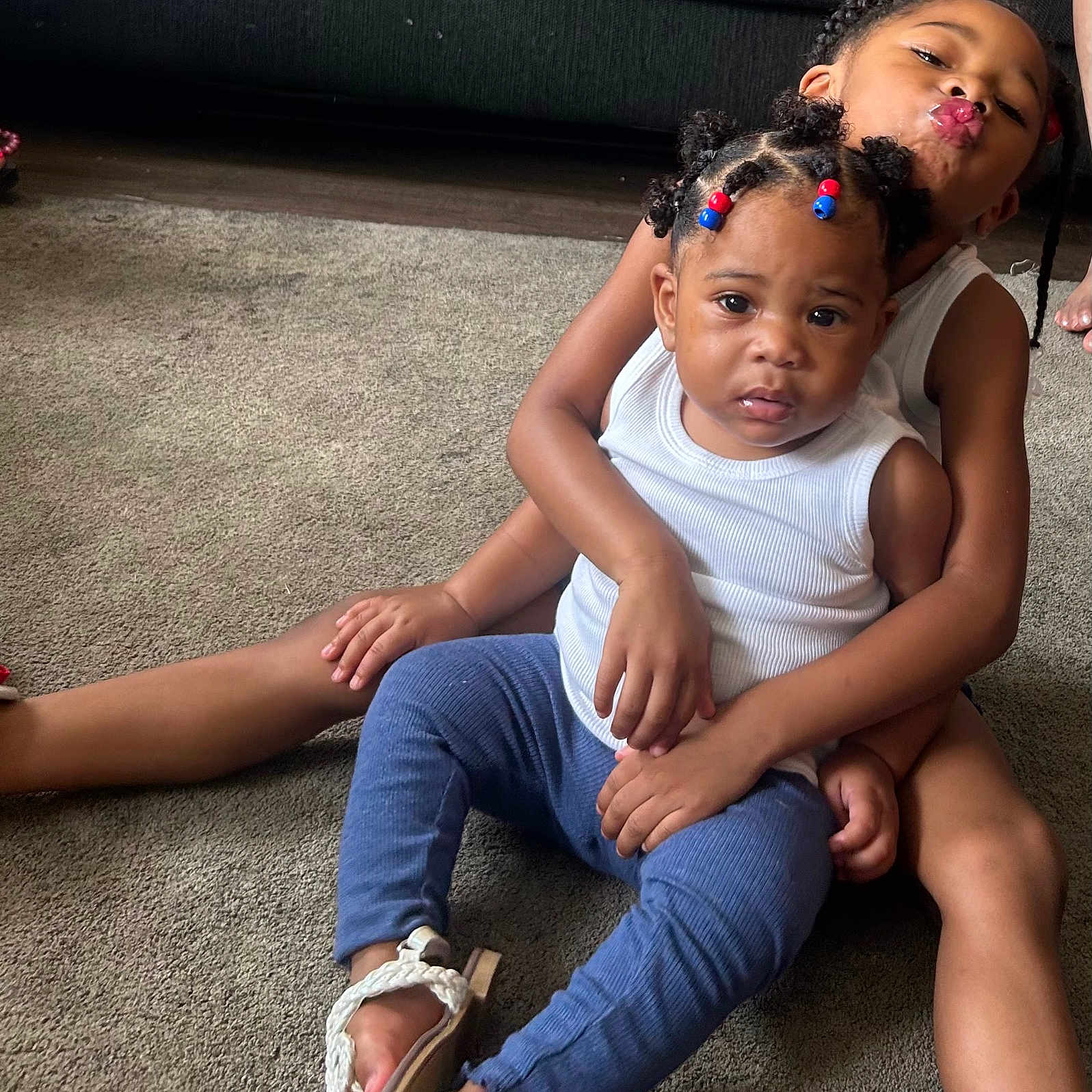 Armani is registered to the contest to win money with this photo: affection, baby, beads, blue_pants, braided_hair, candid, carpet, child, children, couch, cute, family, indoor, playful, portrait, sandals, sitting, smiling, toddler, white_shirt