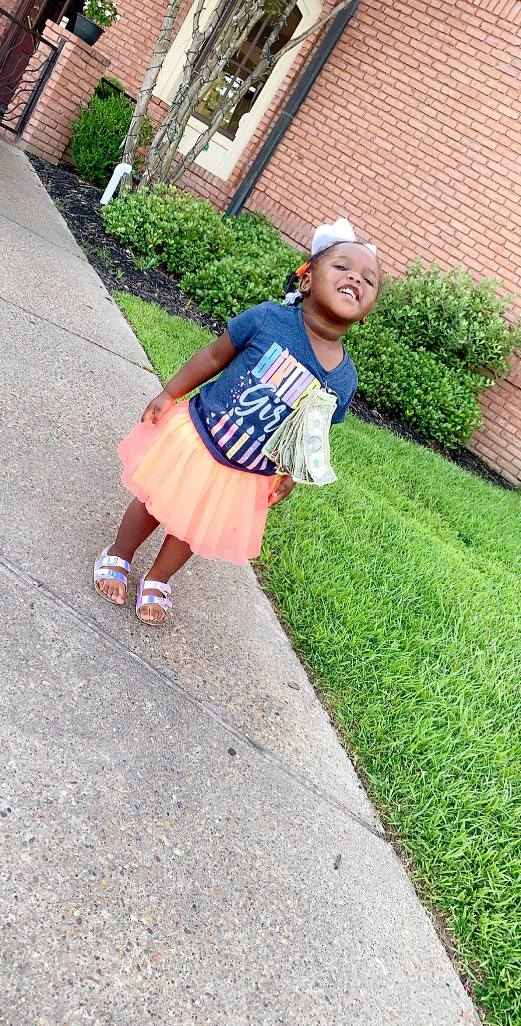 Marley is registered to the contest to win money with this photo: asphalt, child, denim, footwear, fun, grass, headwear, joy, lawn, person, plant, shoe, sidewalk, smile, summer, t_shirt, vacation