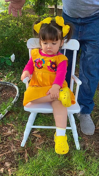 Flor joined the competition — help win amazing prizes! baby_toddler_clothing, chair, child, clothing, dress, face, fun, grass, happy, hat, human_leg, leg, person, plant, shoe, sitting, sneakers, tire, toddler, wheel