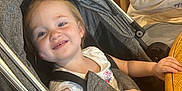 Olivia joined the competition — help win amazing prizes! toddler, stroller, smiling, child, baby, person, indoor, restaurant, table, chair, family, casual, clothing, holding, wooden_furniture, seat_belt, happy, face, head, parent