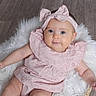 baby, infant, pink_dress, headband, bow, fluffy_cushion, white_fur, wooden_floor, cute, portrait, smile, child, sitting, indoors, young, person, fashion, soft_texture, relaxing, adorable