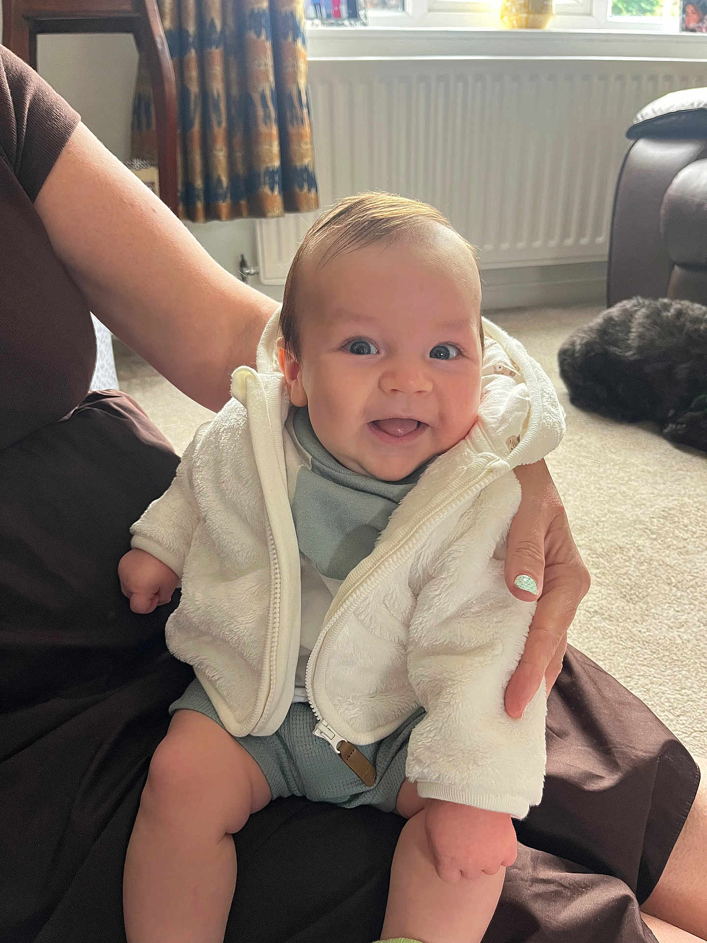 Luca joined the competition — help win amazing prizes! baby, smile, child, fleece_jacket, adult_hand, indoor, carpet, dog, window, curtains, sunlight, happy, sitting, person, face, cozy, home, pet, animal, casual