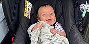 Luca joined the competition — help win amazing prizes! baby, car_seat, blanket, blue_eyes, smiling, infant, child, toy, striped_clothing, black_car_seat, fabric, cute, happy, indoors, person, seatbelt, comfort, sitting, playful, young_child