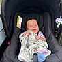 baby, black_car_seat, blanket, blue_eyes, car_seat, child, comfort, cute, fabric, happy, indoors, infant, person, playful, seatbelt, sitting, smiling, striped_clothing, toy, young_child