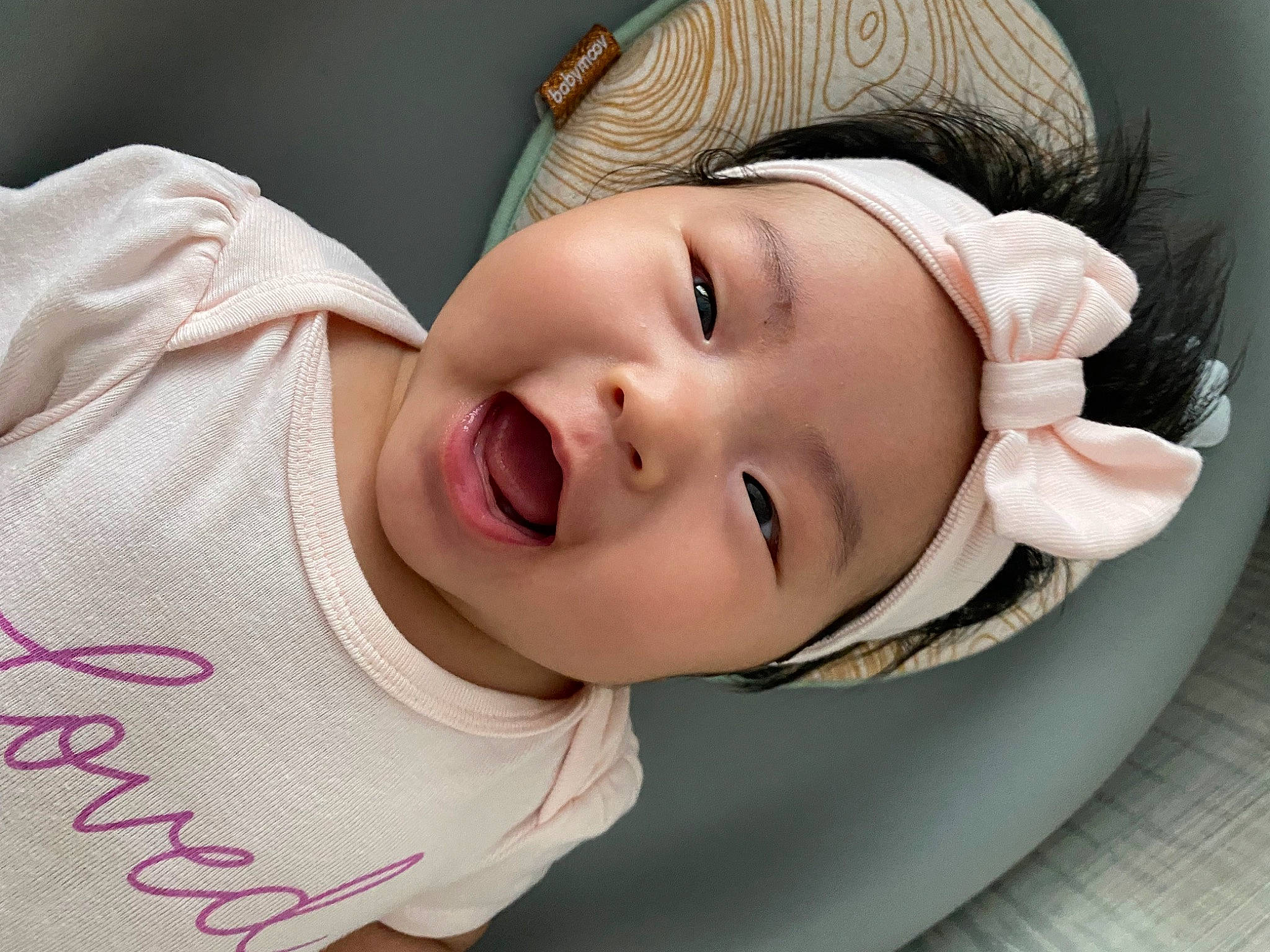 Mia is registered to the contest to win money with this photo: baby, baby_toddler_clothing, cheek, child, comfort, eye, eyebrow, eyelash, flash_photography, happy, headwear, lip, mouth, neck, nose, person, pink, skin, sleeve, smile