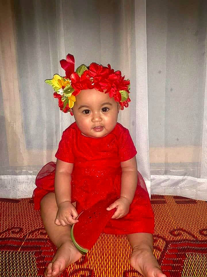 Ayoko Barnabas joined the competition — help win amazing prizes! child, child_model, costume, fashion_accessory, flower, hair_accessory, headgear, person, plant, red, sitting, smile, toddler