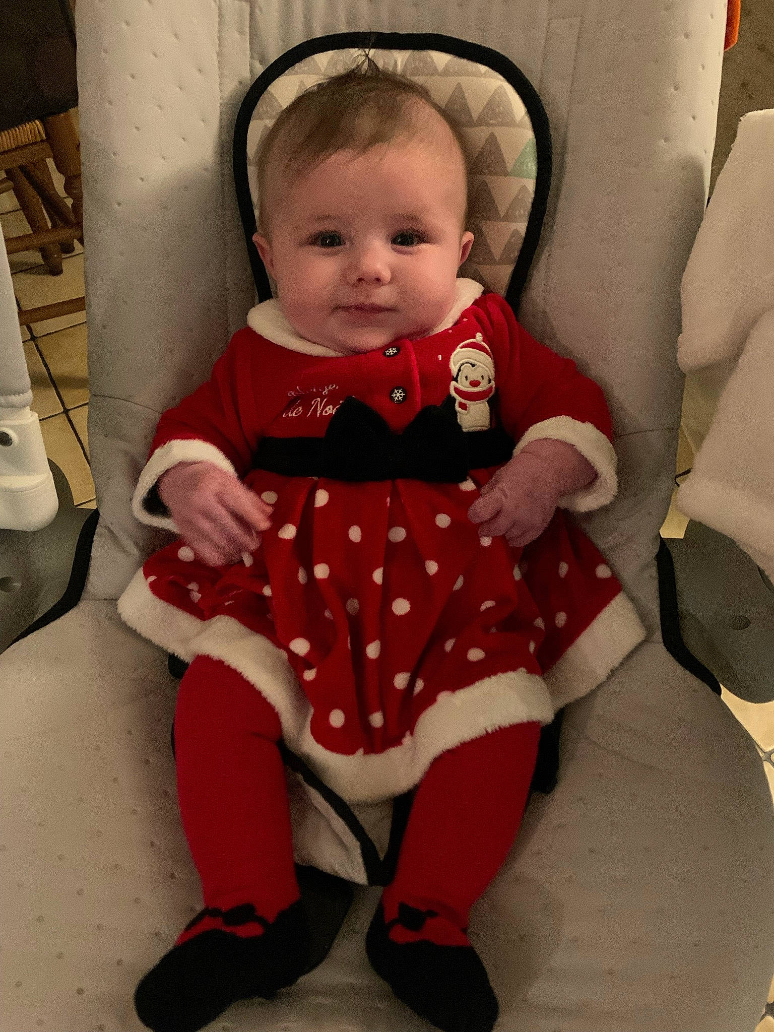 Izia participe au concours pour gagner de l'argent avec cette photo : arm, baby, baby_products, baby_toddler_clothing, cheek, child, collar, comfort, dress, hair, head, human_body, knee, lap, pattern, person, sitting, sleeve, sock, thigh