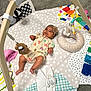 baby, infant, play_mat, toy, wooden_toy, headband, romper, colorful, soft_toy, floor, carpet, child, cute, smiling, lying_down, indoor, playtime, fabric, patterned, happy