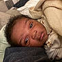 Yanis is registered to the contest to win money with this photo: baby, blanket, infant, face, sleeping, cozy, cushion, clothing, person, indoors, resting, closeup, young_child, soft_texture, curly_hair, portrait, warm_colors, comfort, toddler, sleepwear