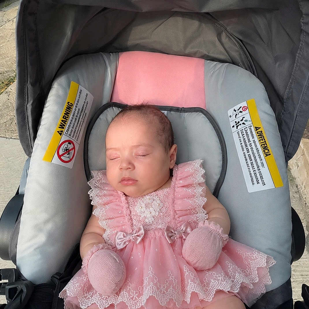 Zohary is registered to the contest to win money with this photo: baby, sleeping, pink_dress, mittens, stroller, car_seat, infant, lace, cute, adorable, child, outdoor, sunlight, peaceful, portrait, young_child, clothing, baby_girl, resting, seat