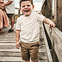 child, toddler, boy, smiling, happy, walking, boardwalk, wooden, railing, family, couple, outdoor, casual_clothing, shorts, white_shirt, shoes, nature, sky, love, affection