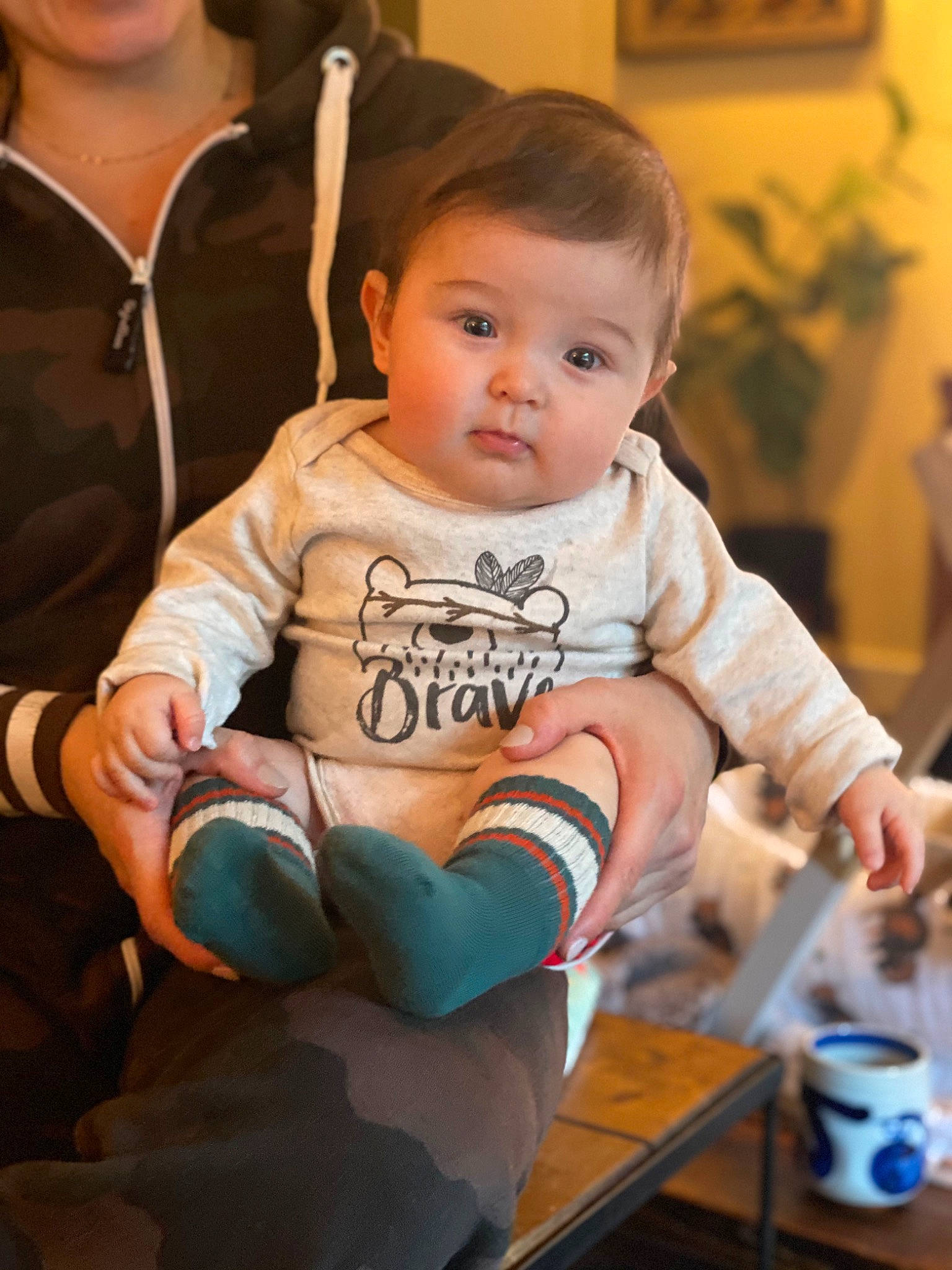 Mayan is registered to the contest to win money with this photo: baby, baby_products, baby_toddler_clothing, cheek, child, finger, fun, happy, head, houseplant, human_body, person, picture_frame, plant, sitting, skin, sleeve, t_shirt, tableware, thumb