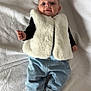 baby, infant, child, blanket, vest, fur_vest, jeans, socks, clothing, lying_down, portrait, cute, soft_texture, indoor, person, newborn, casual_wear, smiling, young_child, closeup
