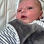 baby, infant, face, closeup, striped_clothing, grey_vest, soft_texture, lying_down, young_child, skin, head, eyes, mouth, cheeks, indoors, blanket, fabric, newborn, person, portrait