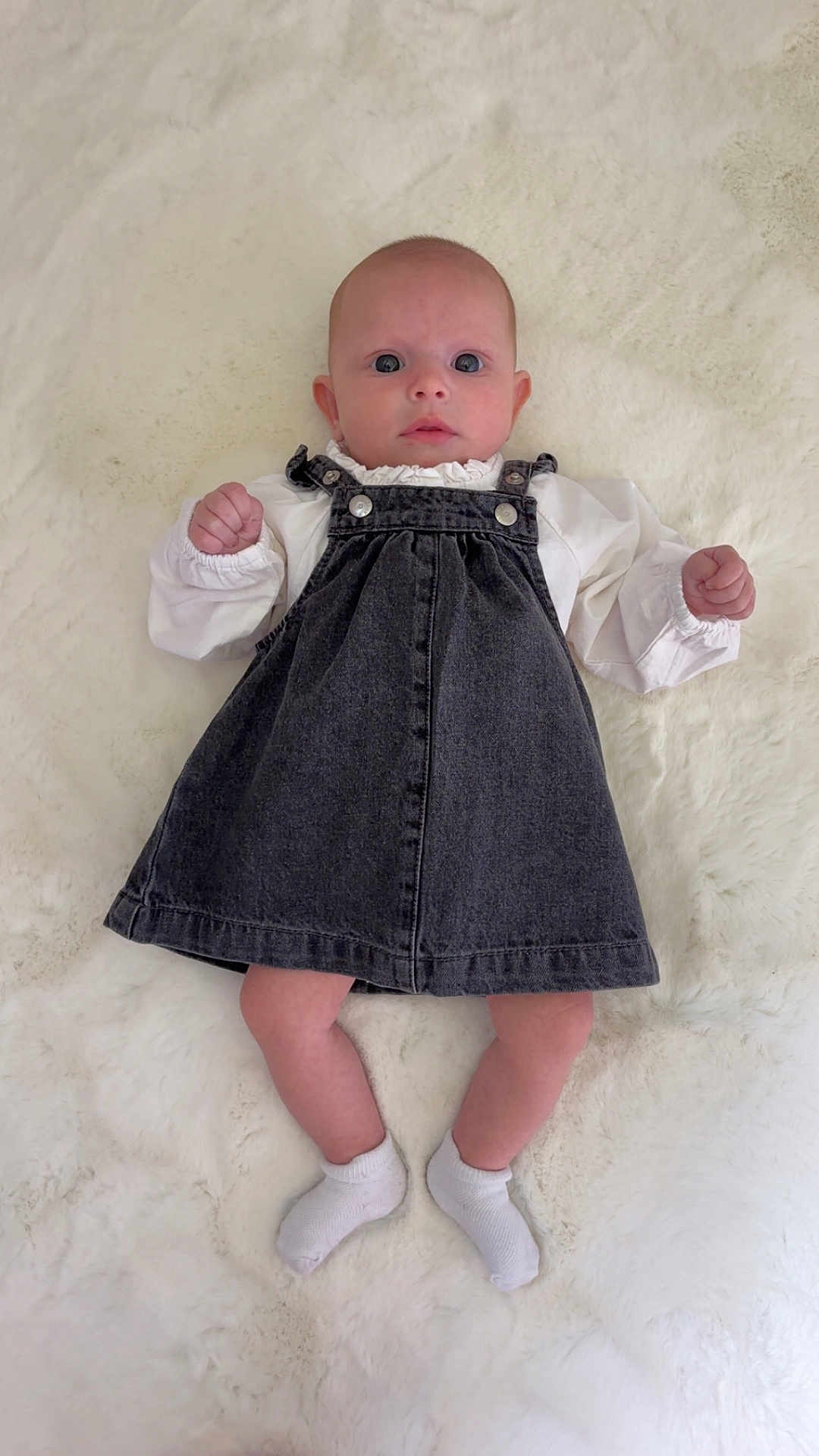 Léane participe au concours pour gagner de l'argent avec cette photo : baby, infant, child, denim_dress, white_socks, blanket, lying_down, curious_expression, cute, portrait, face, head, skin, hands, feet, clothing, indoors, soft_texture, young, person