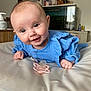 baby, infant, smiling, blue_clothing, pacifier, lying_down, indoors, furniture, fish_tank, household_items, face, hand, head, eyes, skin, cute, happy, soft_surface, child, portrait