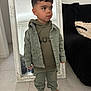 Nino a rejoint le concours — aidez-le/la à gagner de superbes lots ! child, toddler, barefoot, mirror, hoodie, cargo_pants, green_clothing, pout, floor_tile, sofa, pillow, indoor, portrait, casual, stylish, home, reflection, young_child, curly_hair, person