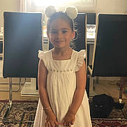 Yara a rejoint le concours — aidez-le/la à gagner de superbes lots ! bag, black_cat, bracelet, carpet, cat, chair, child, curtains, floor, furniture, girl, headband, home, indoor, person, pet, smile, table, white_dress, window