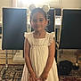 bag, black_cat, bracelet, carpet, cat, chair, child, curtains, floor, furniture, girl, headband, home, indoor, person, pet, smile, table, white_dress, window