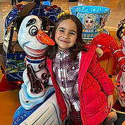 Yara a rejoint le concours — aidez-le/la à gagner de superbes lots ! amusement_ride, background, child, clothing, colorful, entertainment, floor, fun, girl, happy, indoor, lights, people, plaid_shirt, play_area, portrait, red_jacket, smile, snowman, toy