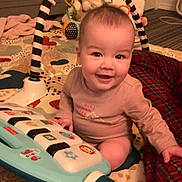 Charlotte joined the competition — help win amazing prizes! baby, infant, smiling, play_mat, toy_keyboard, activity_arch, baby_toy, crib, blanket, pajamas, indoor, sitting, happy, plush_toy, nursery, face, eyes, cheeks, playtime, floor