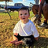 Evan joined the competition — help win amazing prizes! baby, child, grass, outdoor, sunlight, smile, white_shirt, black_shorts, person, dog, chair, pickup_truck, blue_sky, clouds, shadow, barefoot, happy, sitting, pet, summer