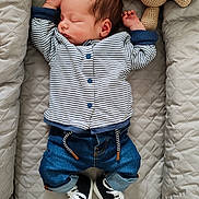 Louis participe au concours pour gagner de l'argent avec cette photo : baby, newborn, sleeping, striped_shirt, denim_pants, sneakers, quilted_cushion, crocheted_toy, teddy_bear, infant, cozy, indoor, cute, child, soft_lighting, peaceful, portrait, clothing, resting, small_hands